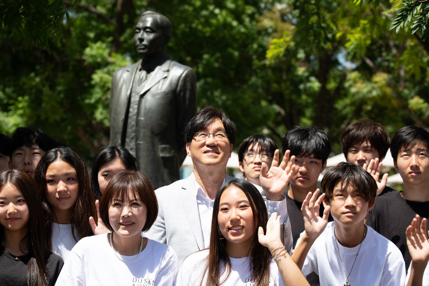 President David Kwak looking up at the Dosan statue, with young people gathered before it